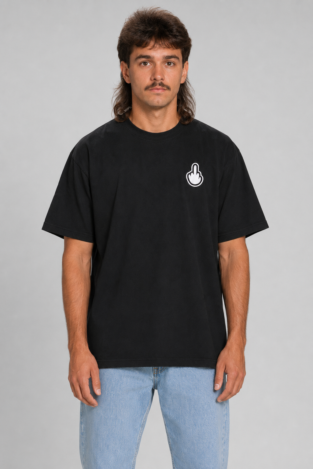 A man wearing a black short-sleeve t-shirt with a small white hand graphic on the left chest, paired with light blue jeans, standing against a solid gray background. #black